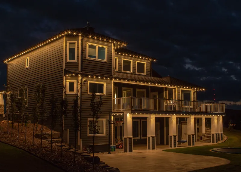 Three storeys of deck and roofline lighting on a hillside home