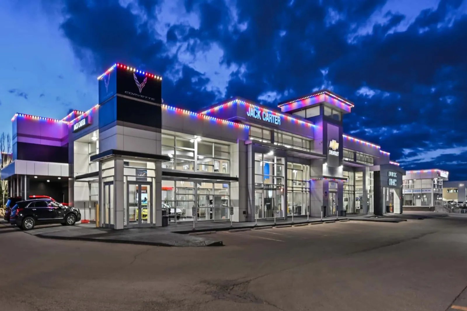 Retail plaza at dusk with colored permanent lights along its rooflines and parapets
