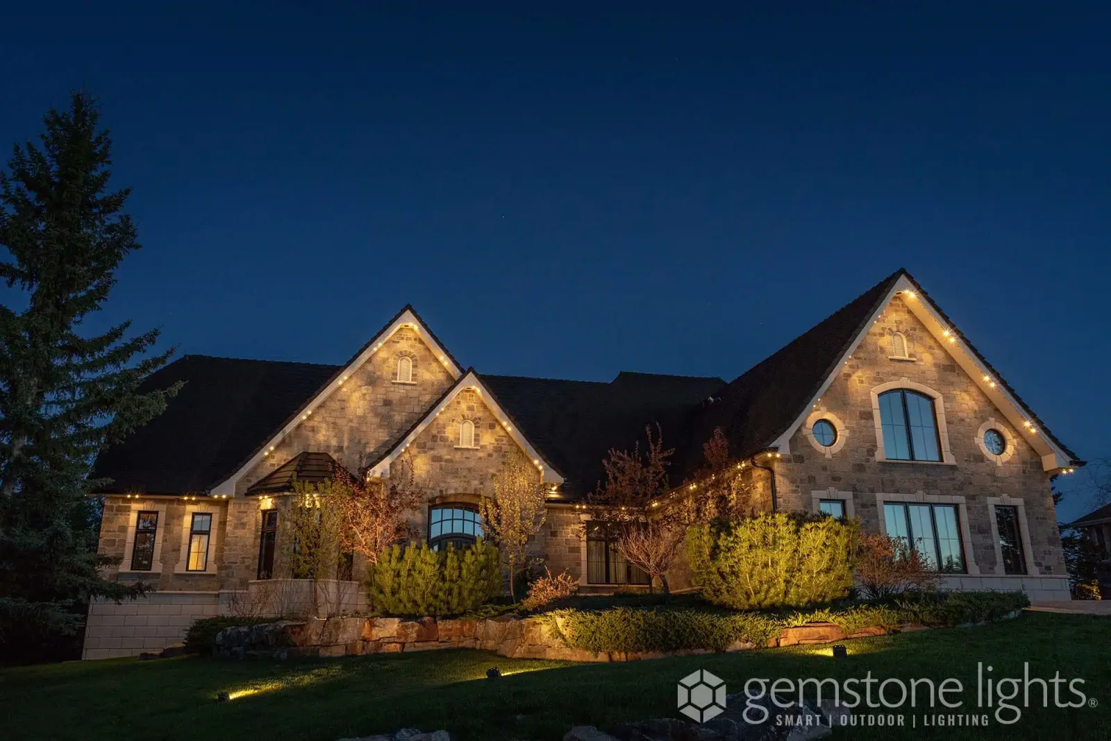 Stone home with roofline and garden lighting