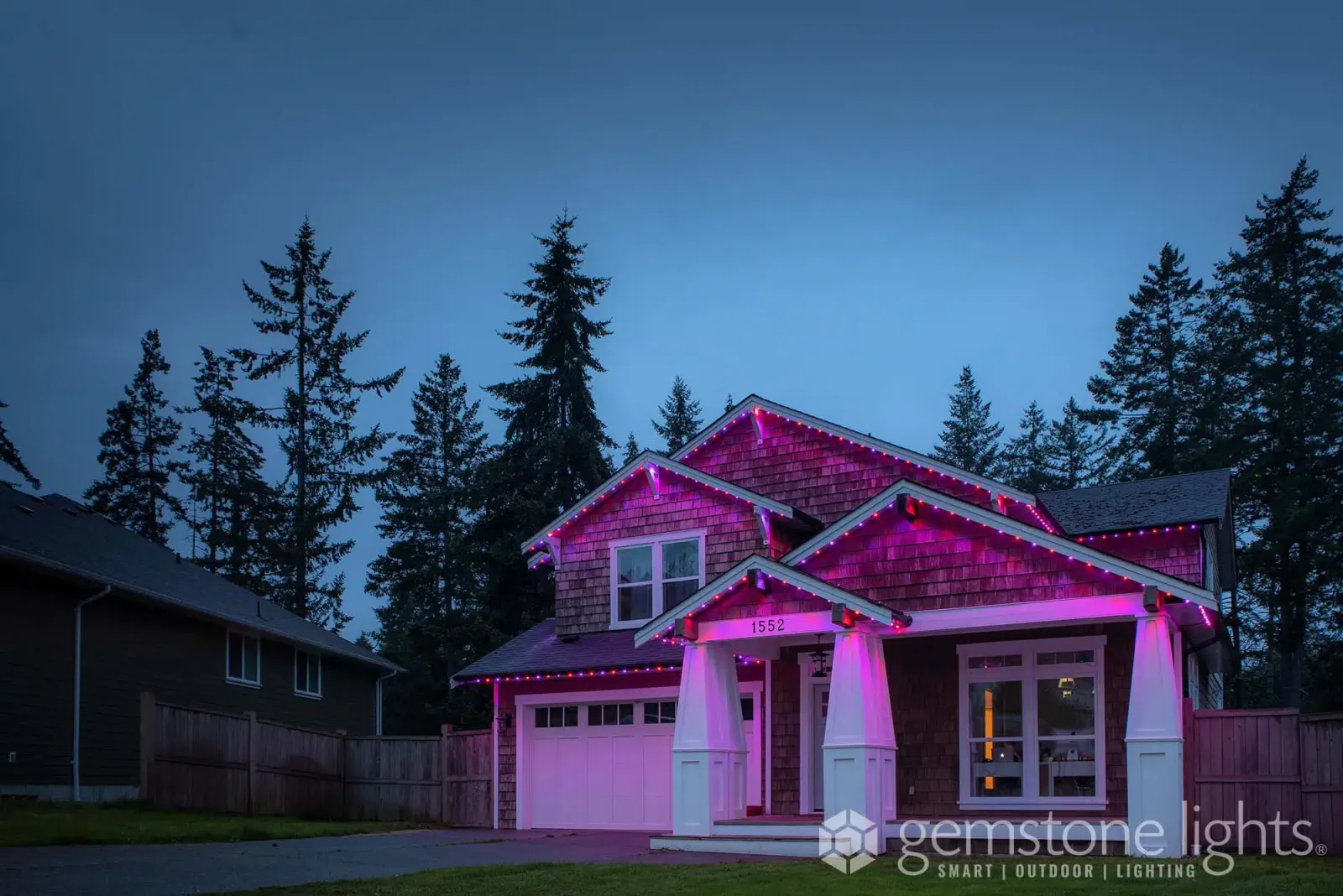 Craftsman-style home with tapered porch columns and gables lit in soft pink at dusk
